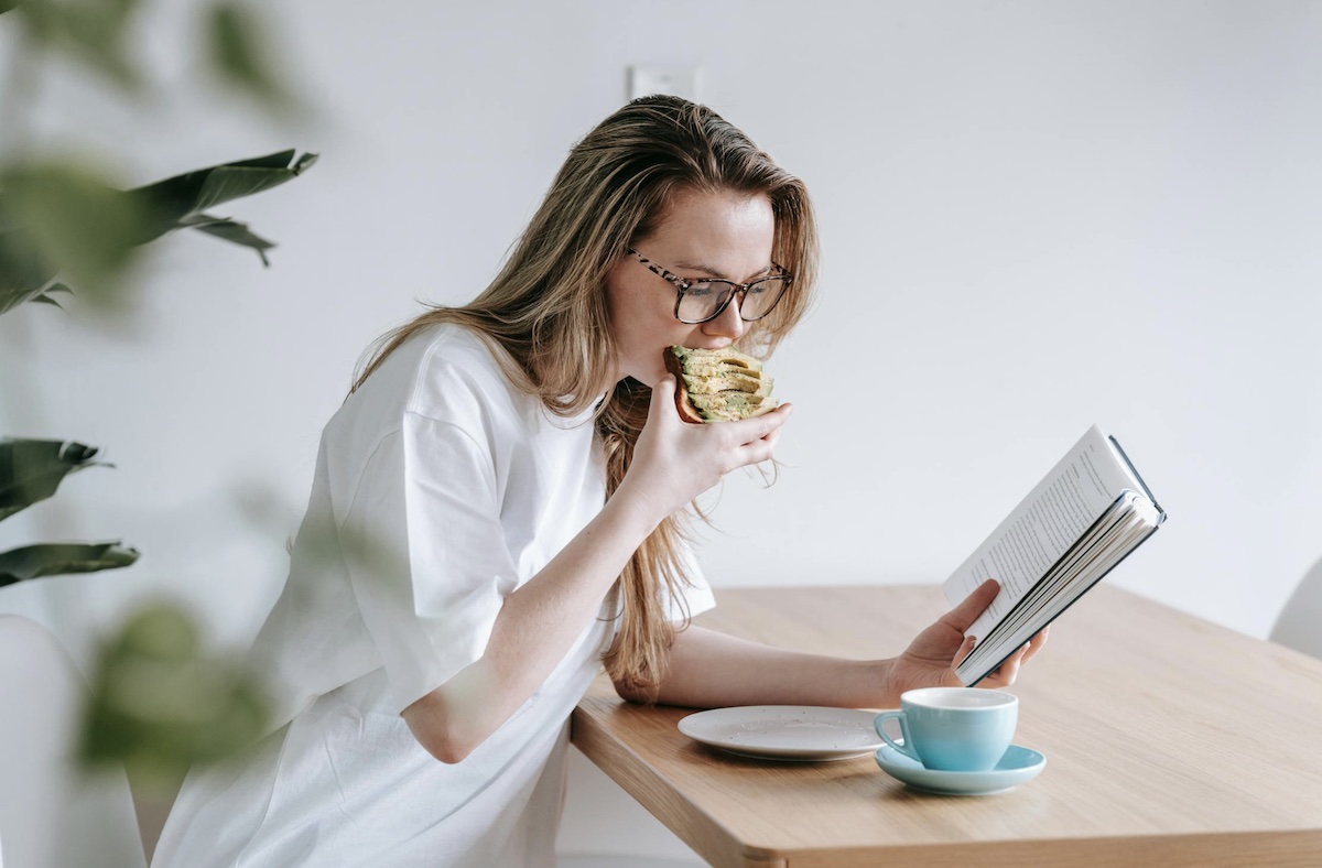 Woman eating and reading a book alone