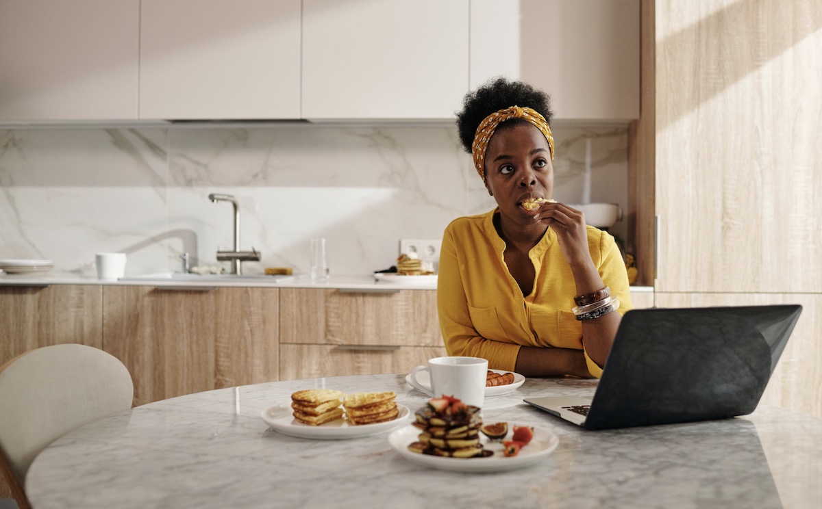 Woman eating alone in kitchen Image: Pexels - Diva Plavalaguna