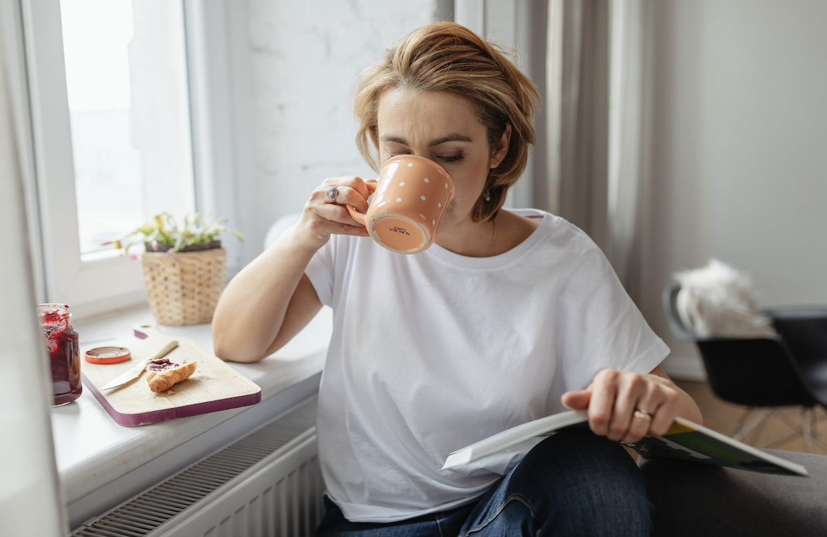 Woman drinking coffee and reading book