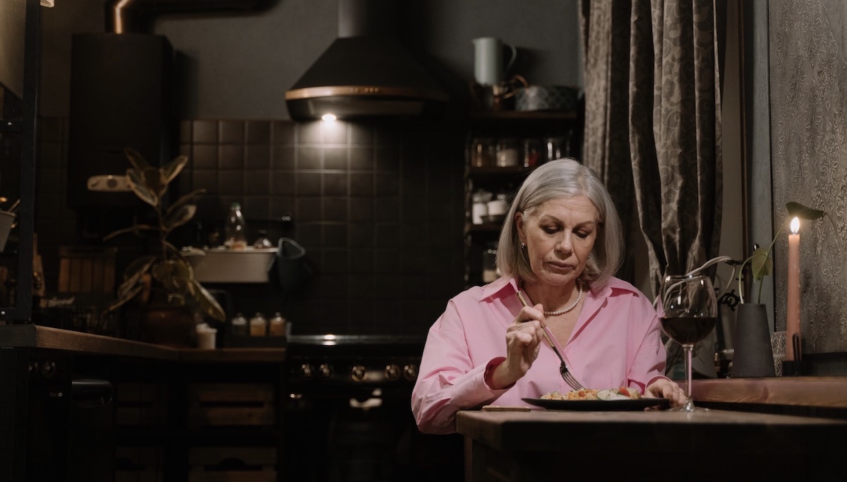 Woman eating dinner with a glass of wine. Image: Pexels - cottonbro studio