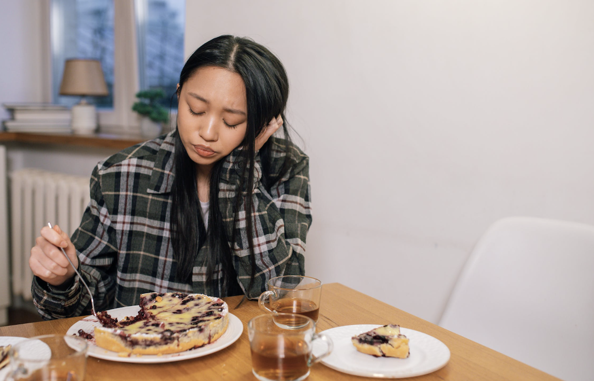 Woman sitting and eating a cake upset. 