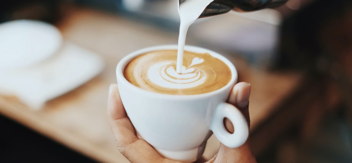 Pouring milk into a coffee. Unsplash - Fahmi Fakhrudin