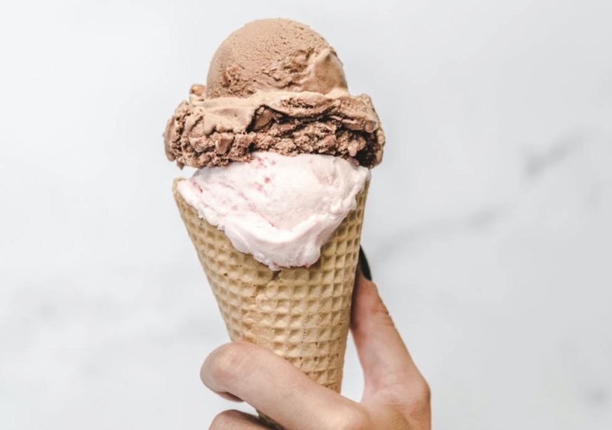 Individual holding ice cream in a cone 