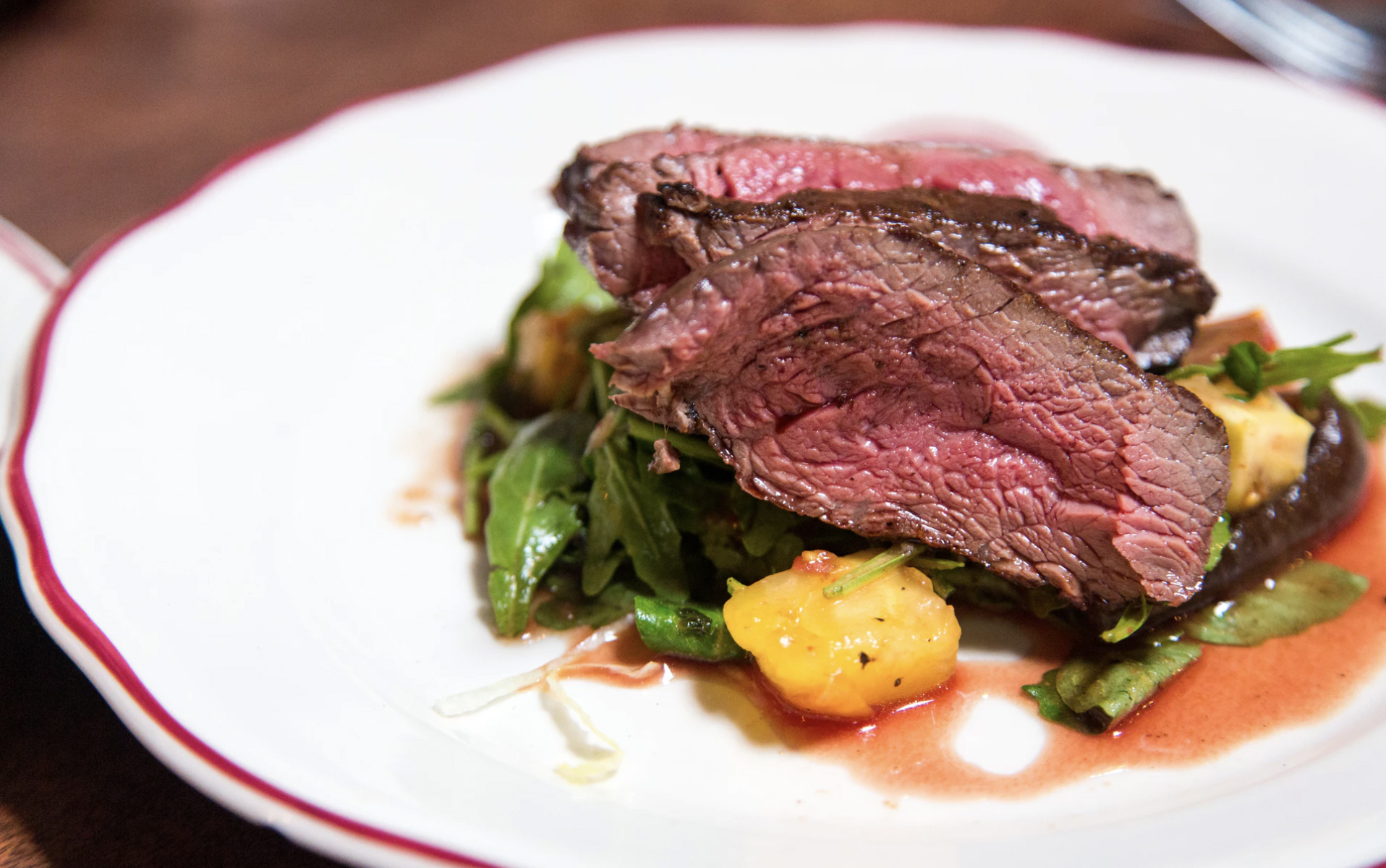 A piece of red meat served on a plate with vegetables